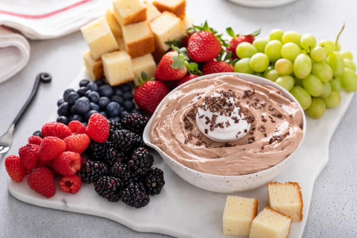 White platter filled with pound cake, fresh fruit, and a bowl of nutella fruit dip.