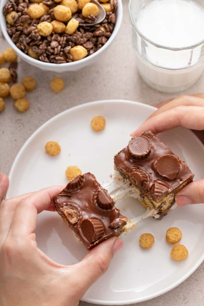 Hands pulling apart the two halves of a peanut butter cup rice krispie treat.