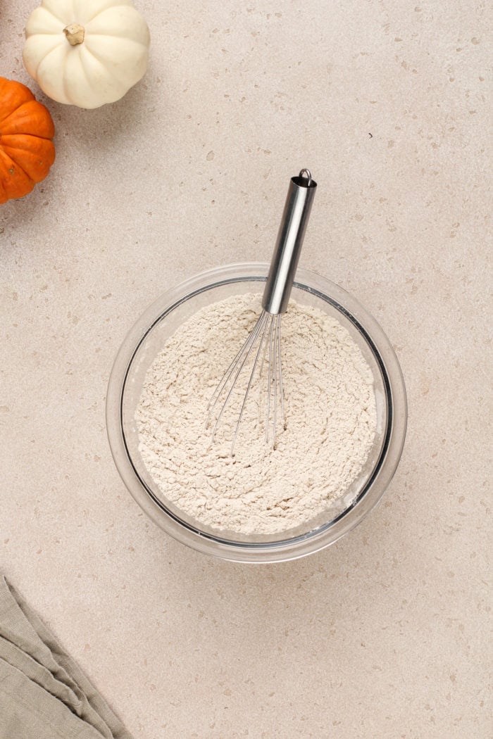 Dry ingredients for pumpkin banana bread being whisked in a glass mixing bowl.