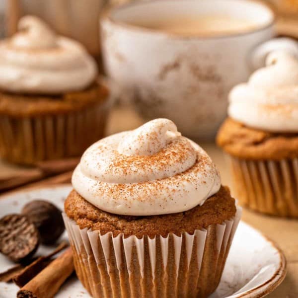 Pumpkin spice cupcake on a white plate, with more cupcakes in the background