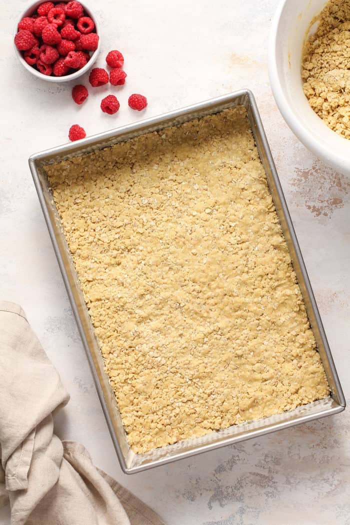 Bottom crust for raspberry bars pressed into the bottom of a metal baking pan