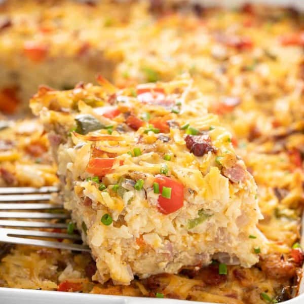 Spatula lifting a slice of hash brown breakfast casserole out of the baking dish