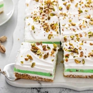 Cake server removing a piece of pistachio pudding dessert from the corner of the layered dessert.