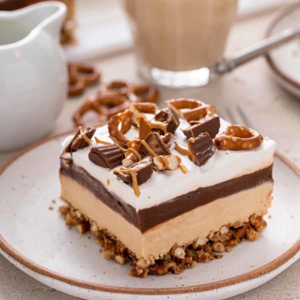 Slice of peanut butter pretzel dessert on a plate showing the layers of the dessert.