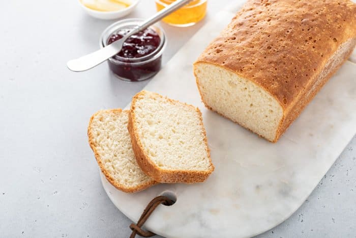 Loaf of english muffin bread set on a marble board, with two slices cut off the end