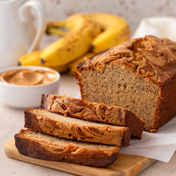 Sliced loaf of peanut butter banana bread on a wooden cutting board.