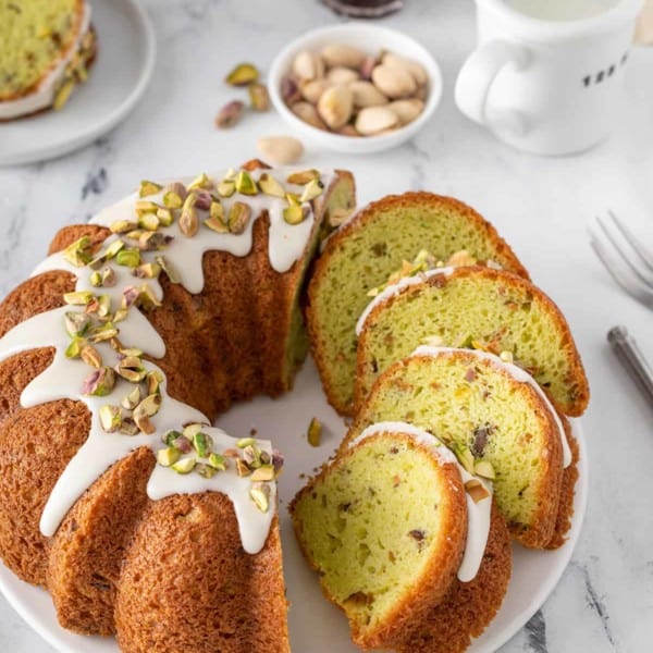 Sliced pistachio pudding cake on a white platter