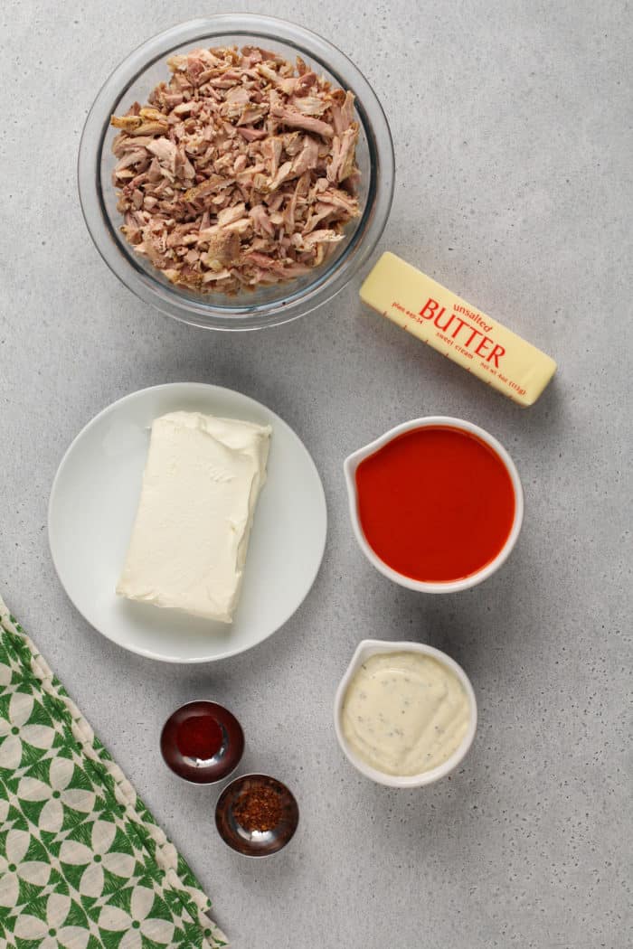 slow cooker buffalo chicken dip ingredients arranged on a gray countertop.