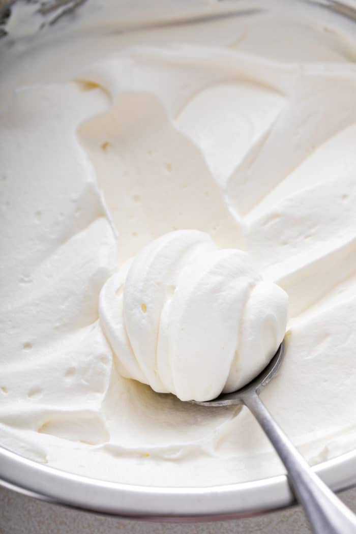 Spoonful of whipped cream frosting set on top of a bowl of the frosting.