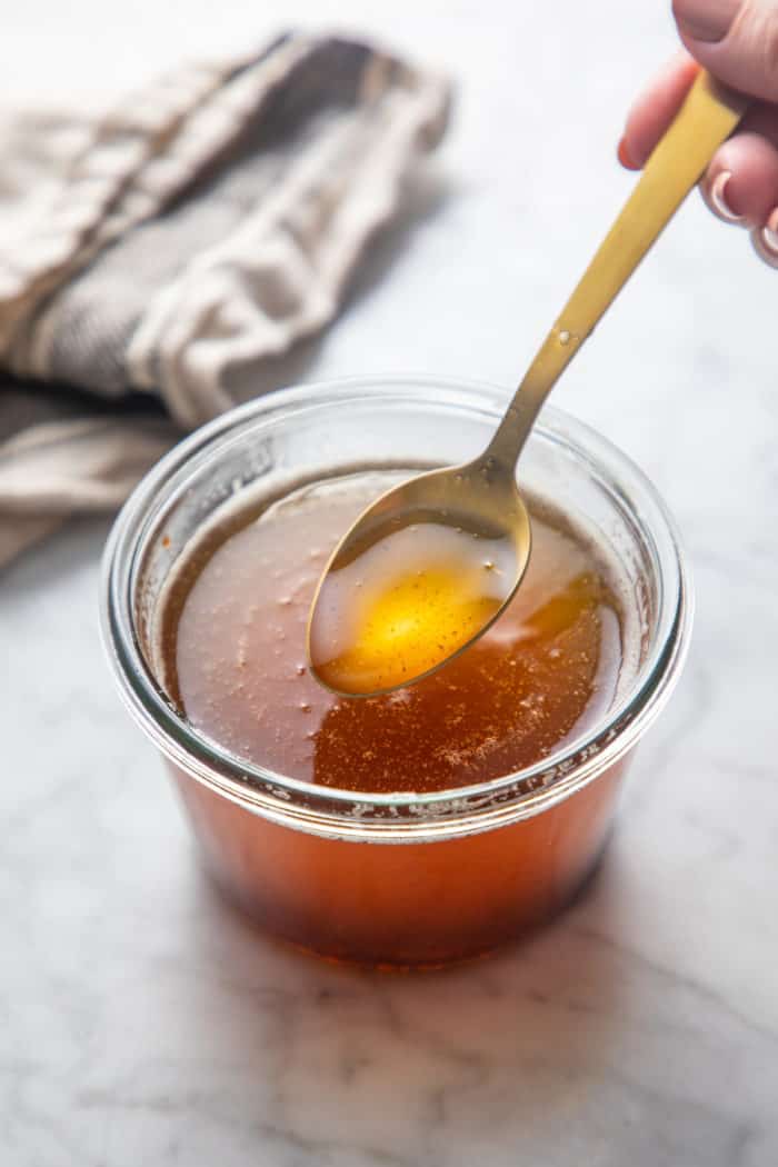 Spoon picking up a bit of brown butter from a jar of brown butter.