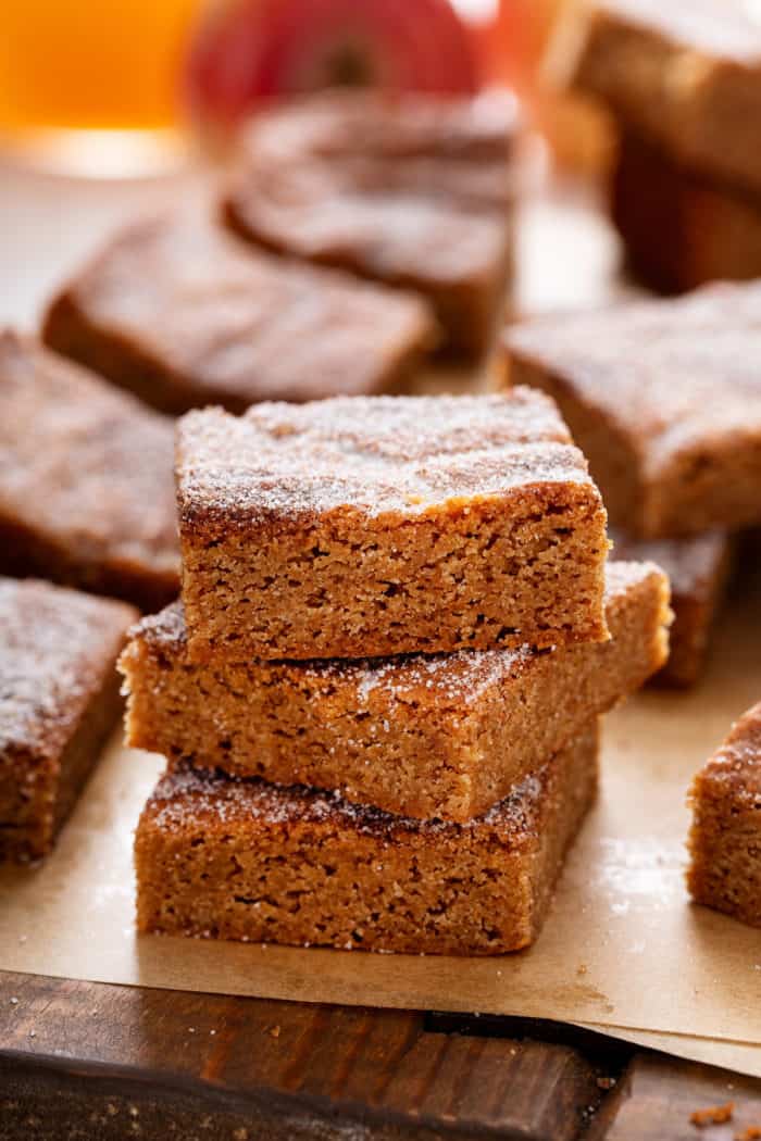 Three apple cider blondies stacked in a piece of brown parchment paper.