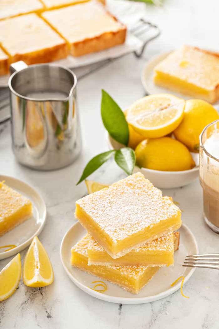 Three sliced lemon bars stacked on a white plate.