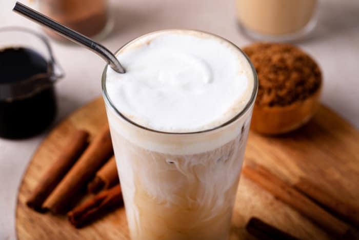 Glass of iced coffee with a straw in it, topped with vanilla sweet cream cold foam.