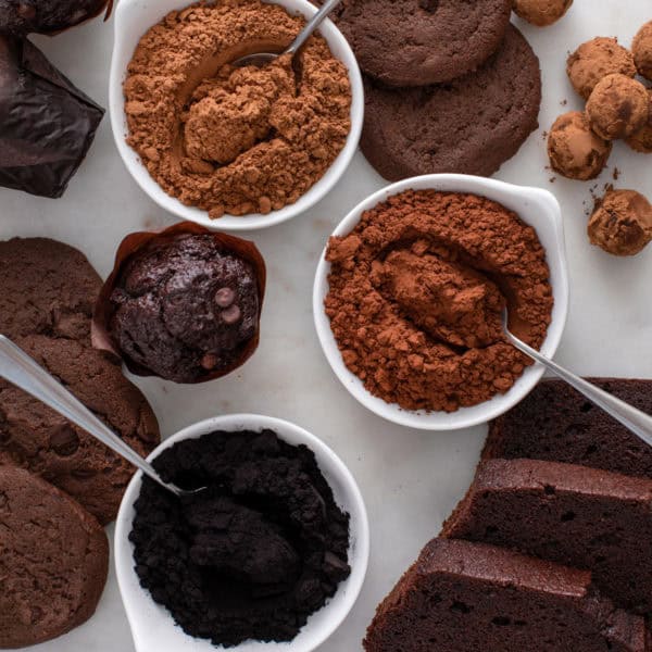 Three bowls, each holding a different type of cocoa powder.