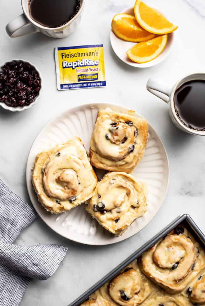 Overhead view of 3 cranberry orange cinnamon rolls on a white plate