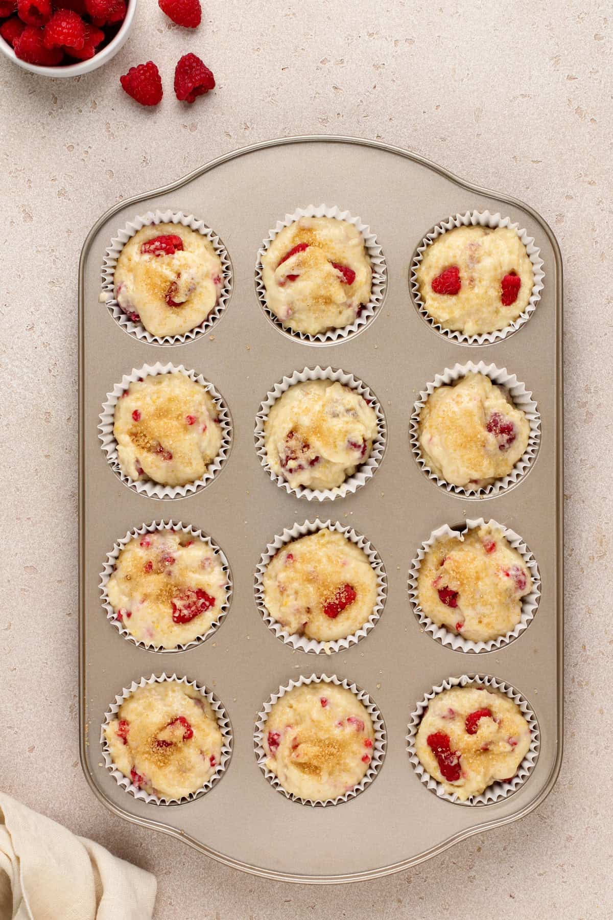 Unbaked lemon raspberry muffins in a muffin pan, ready to go in the oven.