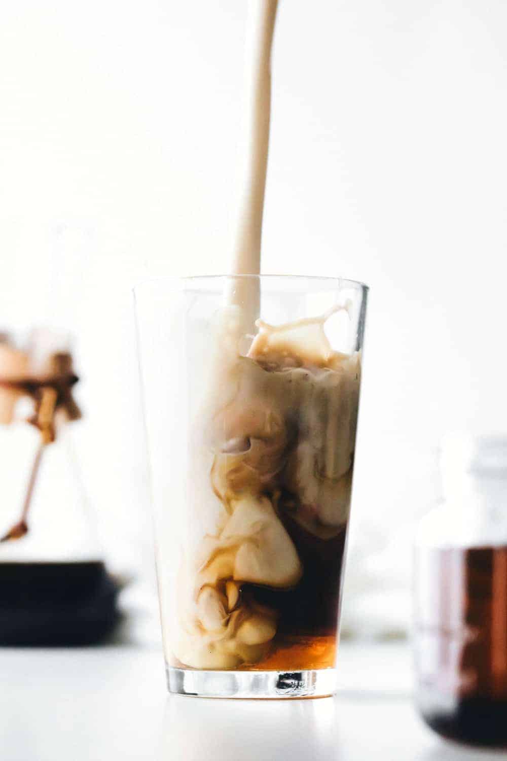 Milk pouring into a glass of iced coffee