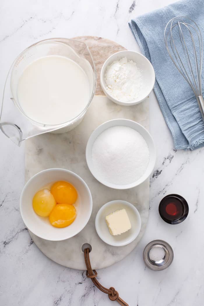 Homemade vanilla pudding ingredients on a marble countertop