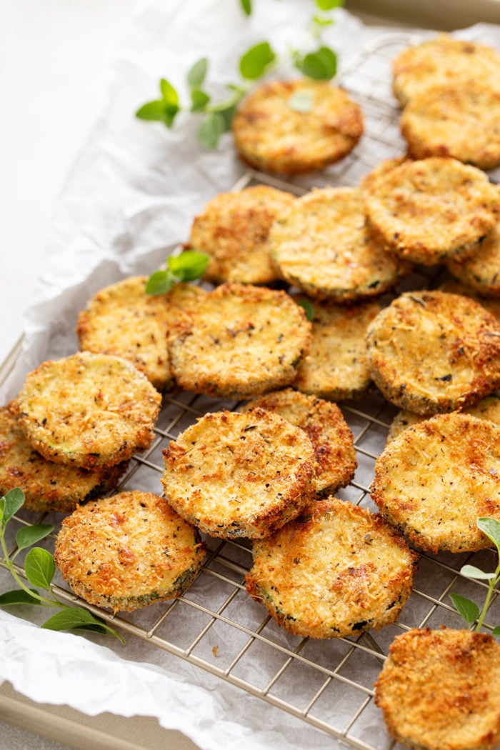 Air fryer zucchini chips on a wire rack set on a rimmed baking sheet.