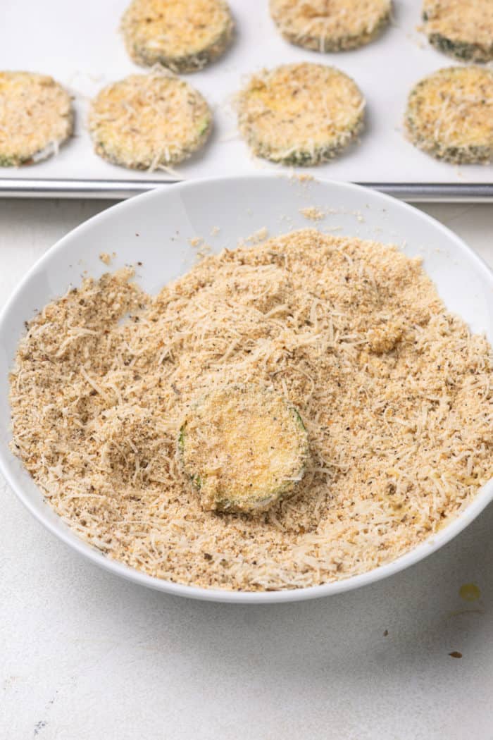 Zucchini round being coated in breadcrumb coating.